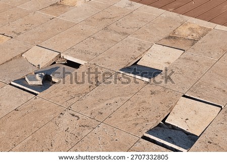 Broken paving creating an uneven surface, depicting neglect, construction issues, maintenance problems, and potential danger