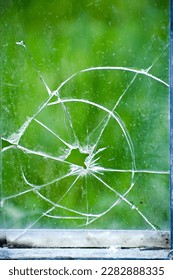 a broken and perforated windowpane in an unoccupied house. - Shutterstock ID 2282888335