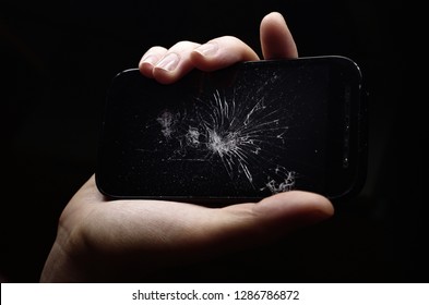 broken phone in hand on dark background, crash phone, fractured, smartphone repair, regret