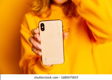 Broken phone in woman's hand. Sad lady holding broken glass and mobile.
