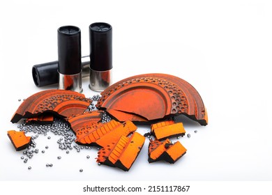 Broken pieces of flying clay pigeon target and shotgun shell bullets on white background , Gun shooting game