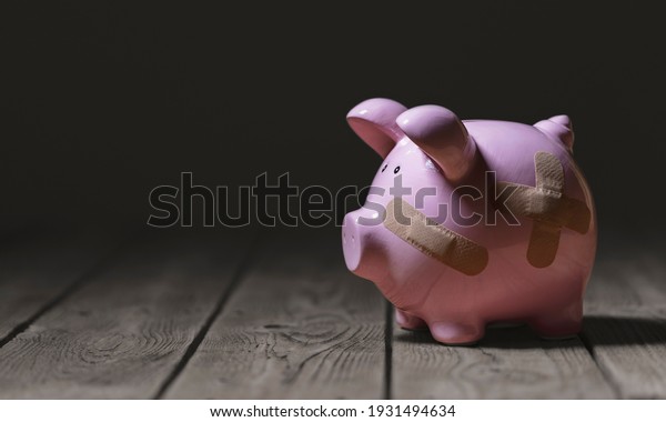 Broken piggy\
bank with band aid bandage or plaster finance background concept\
for economic recession or\
bankruptcy