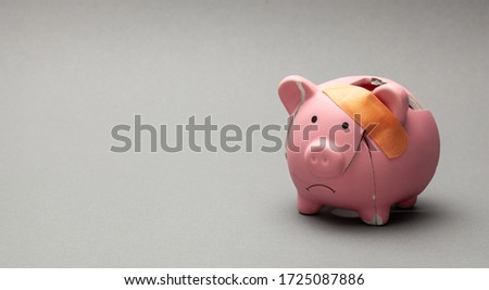 Broken piggy bank with beige adhesive on gray background.