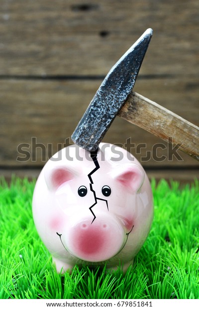 Broken\
piggy bank by hammer, financial crisis\
concept