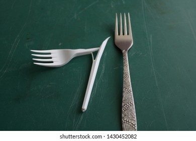 Broken Plastic Fork And Iron Fork On A Green Background.