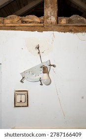Broken plastic light switch and hanging light bulb ripped from a white wall, abstract insurance backdrop