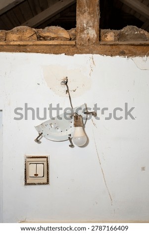 Broken plastic light switch and hanging light bulb ripped from a white wall, abstract insurance backdrop