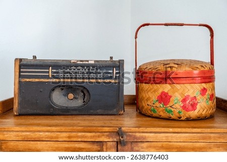 A Broken raido and wicker basket kept ontop a cabinet