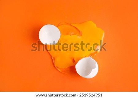 Broken raw egg and shell on orange background, top view