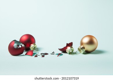 Broken Red Christmas Ball And Safe Two On Light Blue Background. Choose Between Glass Balls Or Plastic Balls Concept.