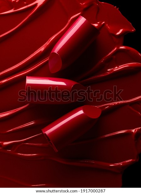Broken red\
lipsticks over smudged lipstick\
background