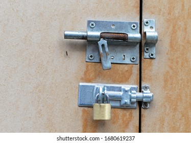 Broken rusty open bolt and newer closed bar lock with copper padlock screwed on fibre board doors with mosquito