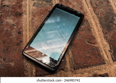 Broken Screen Old Cell Phone On Brick Ground. Selective Focus Image