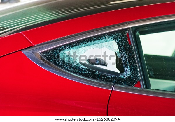 Broken and shattered\
car window. Cracked glass of an automobile. Smash-and-grab\
automobile break-ins.