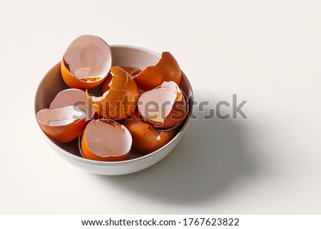 The broken shell of a dozen eggs lies in a plate. Eggshells are a source of calcium.