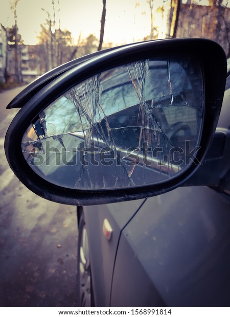 Broken side\
mirror of the car. Cracks in the\
mirror.