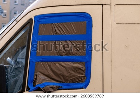 broken side window in a delivery van covered with black foil and tape. securing a broken window in a car after theft from the inside.