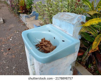 A Broken Sink With Dry Leaves On It 