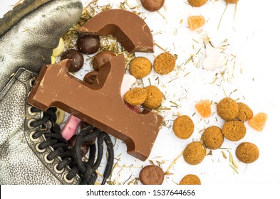 Broken Sinterklaas Chocolate Letter P At Shoe Surrounded With Gingerbread Cookies, Sweets And Hay Residues.