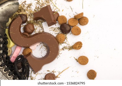 Broken Sinterklaas Chocolate Letter S At Shoe Surrounded With Gingerbread Cookies, Sweets And Hay Residues.