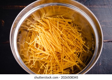 Broken Spaghetti Noodles In A Mixing Bowl: Overhead View Of Uncooked Spaghetti Noodles That Have Been Broken Into Smaller Pieces