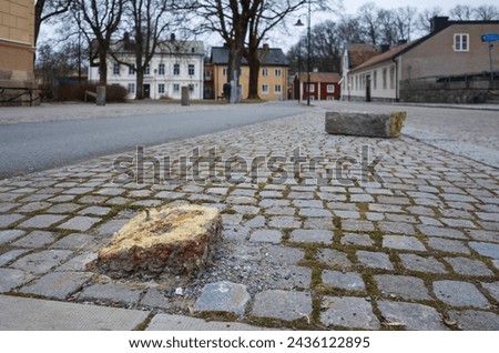 Broken stone pillar or bollard at the border between a road, footpath and bike path in Västerås, damaged public property, city view with selective focus