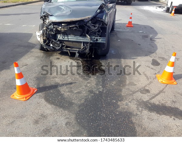 broken suv car\
after a front collision damaged engine compartment of vehicle\
fenced by orange traffic cones drips of spilled oil from the\
engine, nobody accident on sunny\
day.