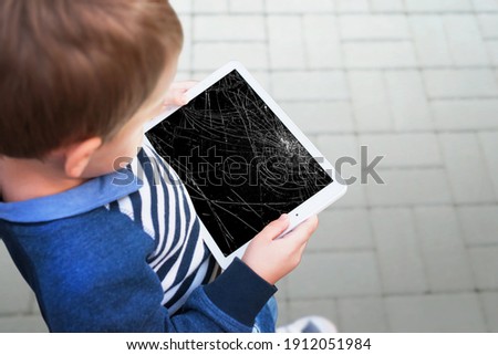 Broken tablet in boy hands concept. Smashed screen after drop