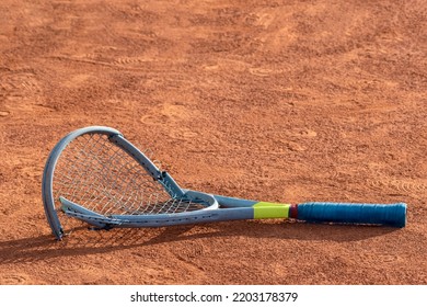 Broken Tennis Racket On Clay Tennis Court. Mental Health Problem In Sports. Negative Emotions, Stress, Dissatisfaction, Defeat, Crash, Failure, Loss Concept