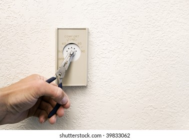 Broken Thermostat Knob. Hand Using Pliers To Turn The Dial