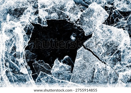 Broken thin ice shards with space for copy. Crushed natural textured ice on a black background, close-up.
