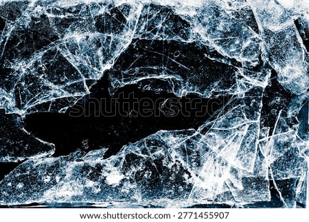 Broken thin ice shards with space for copy. Crushed natural textured ice on a black background, close-up.