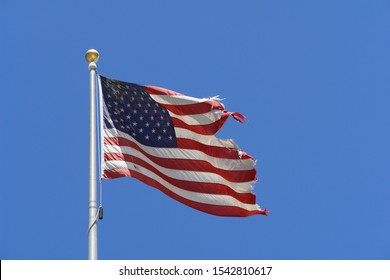 broken torn American flag waving isolated in the background blue sky