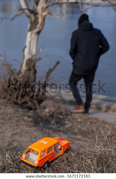 A broken\
toy a car and a man walking away from\
it