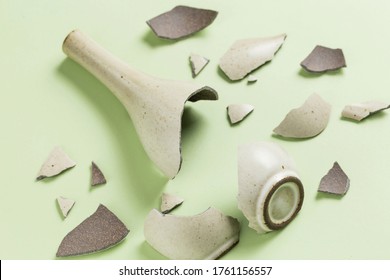 A broken vase against a green background