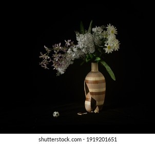 Broken vase and small football on black background