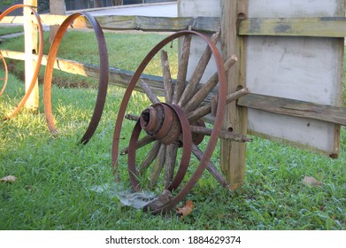 Broken wagon wheel against a fence