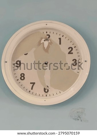 Broken Wall Clock with Missing Hands and Damaged Dial Face.
A damaged white wall clock with missing clock hands and partially peeled dial face, showing deterioration and water damage. The clock face displays visible aging with discoloration and broken glass fragments on the wall below. Concept of broken time, neglect, deadline missed, or the passage of time.