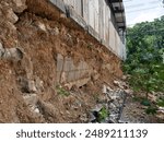 Broken wall with soil erosion from low standard construction.