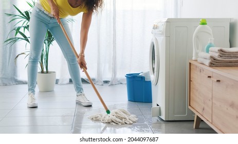 Broken Washing Machine Leaking On The Floor, A Woman Is Cleaning With A Mop