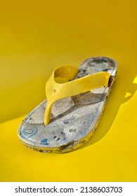 Broken And Wasted Children Flip Flops On Yellow Studio Background