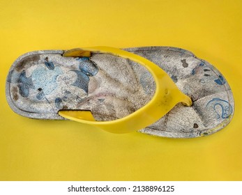 Broken And Wasted Children Flip Flops On Yellow Studio Background Top View