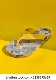 Broken And Wasted Flip Flops On Yellow Studio Background