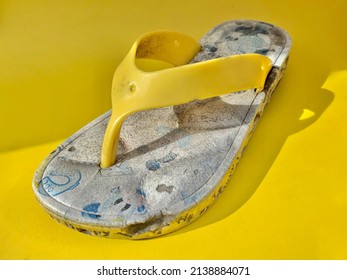 Broken And Wasted Yellow Children Flip Flops On Yellow Horizontal Studio Background