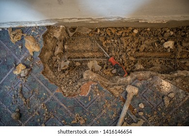 Broken Water Pipe In An Apartment. Visible Hole In The Ground With Tiles, Old Concrete And Debris. Construction Site While Trying To Remedy A Water Leak At Home With Pipe And Closed Valve On The Wall