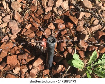 Broken Water Sprinkler Watering Red Rocks In Desert Climate