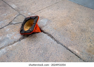 Broken Weathered Sidewalk  With Pot Hole With Orange Cone Upside-down In Hole