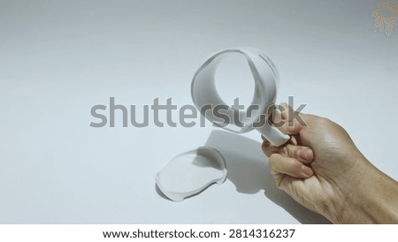 A broken white ceramic mug is shown with its handle still intact, isolated on a white background.