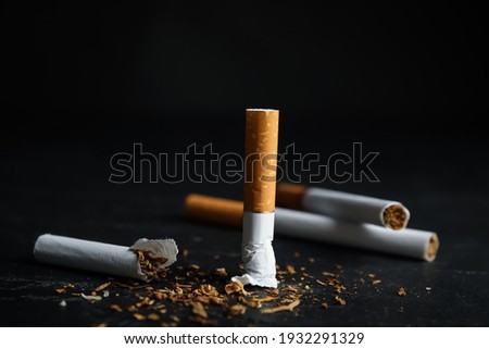 Broken and whole cigarettes on black table, closeup. Quitting smoking concept