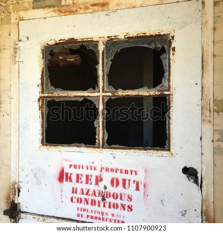 Broken window of abandoned building at historic Northern Michigan Asylum, AKA Traverse City State Hospital. Keep Out; No Trespassing.